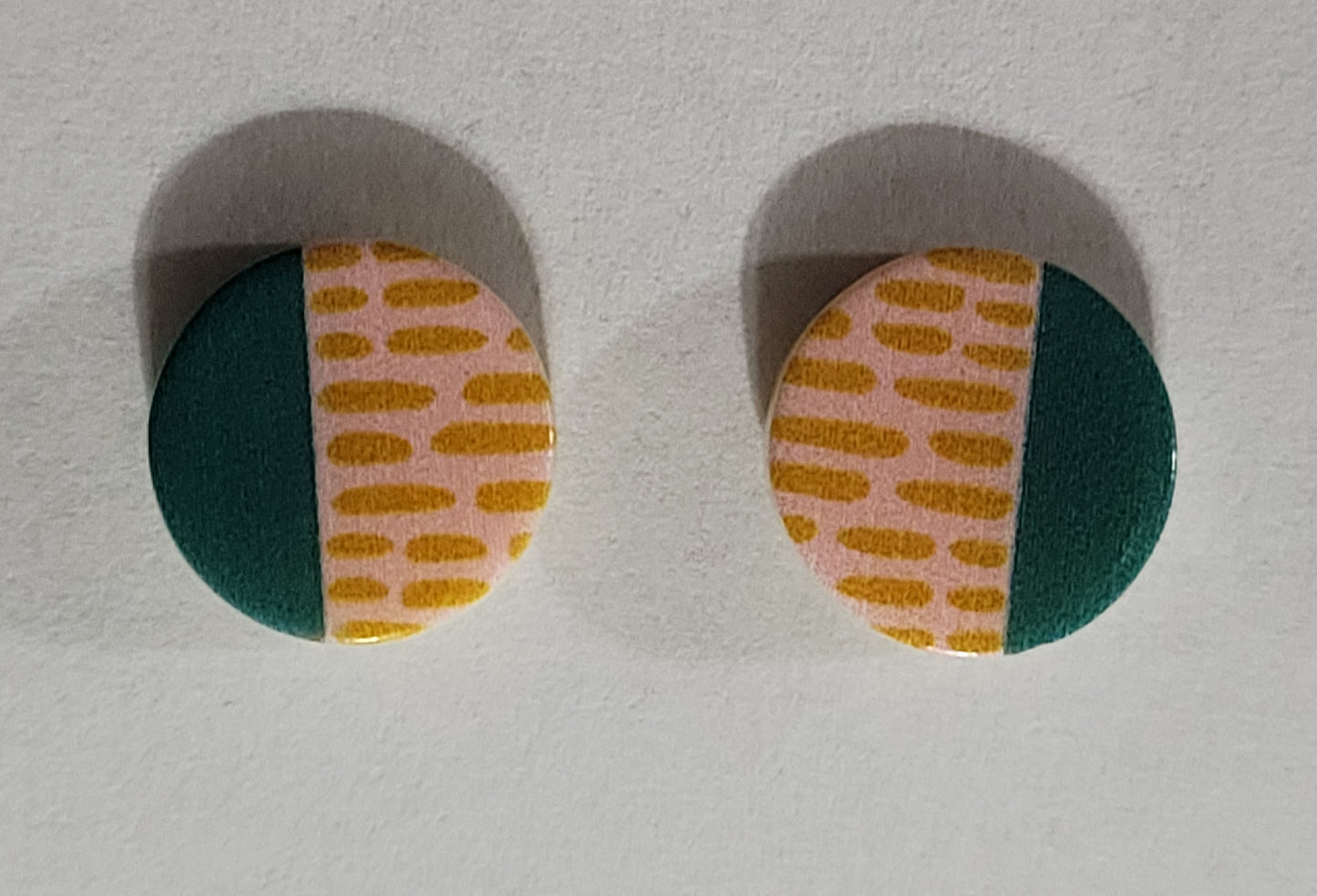 Kids' round button shaped earrings with teal on one half and peach with darker peach lines on the other