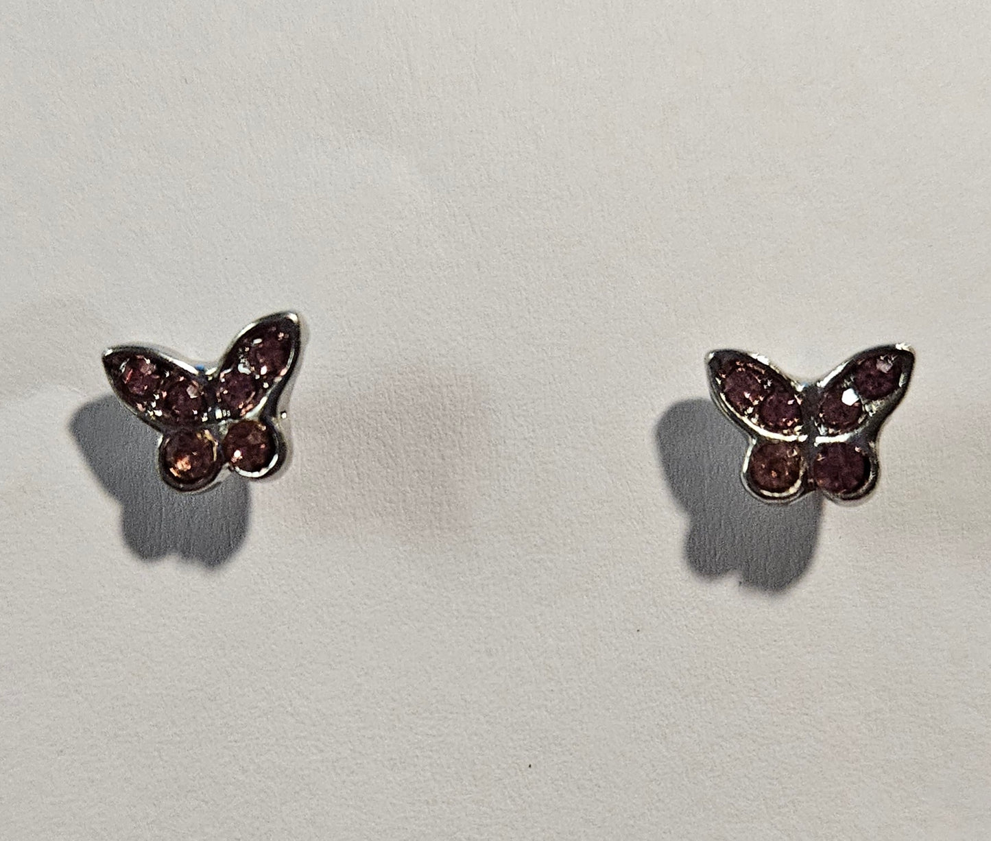 Silver butterfly shaped earrings with pink rhinestones