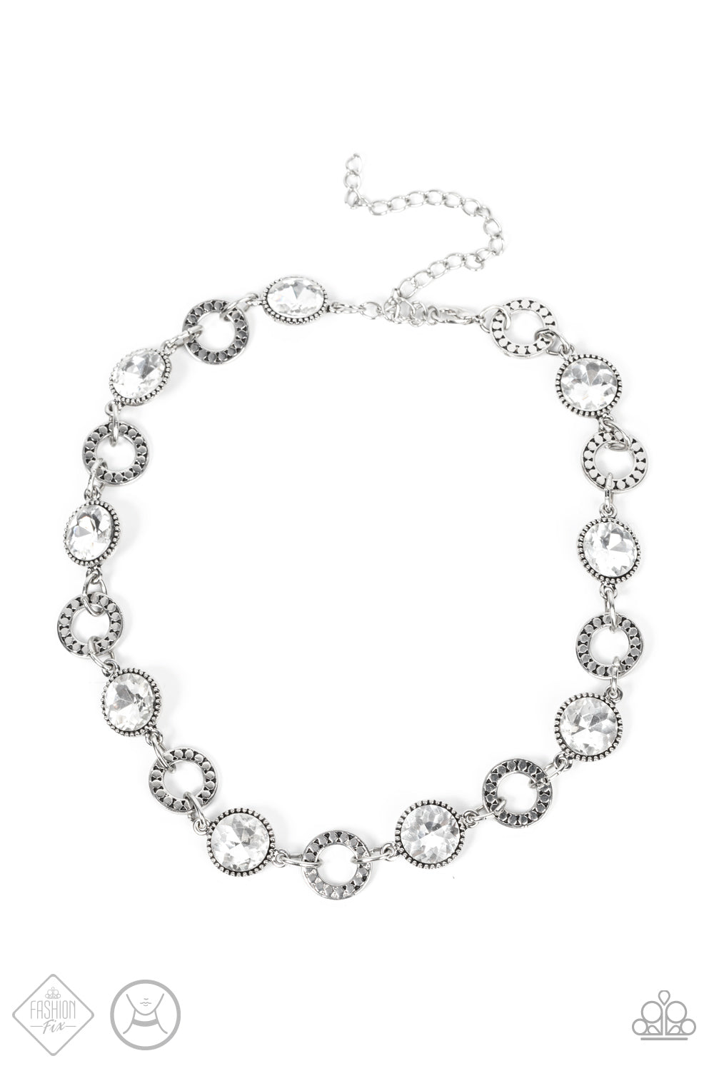 Dramatic white gems encased in daintily dotted frames link with silver rings finished with flattened studded texture. The stunning rhinestones and edgy rings alternate around the neck, resulting in an upscale industrial flair. Features an adjustable clasp closure. Sold as one individual choker necklace. Includes one pair of matching earrings.