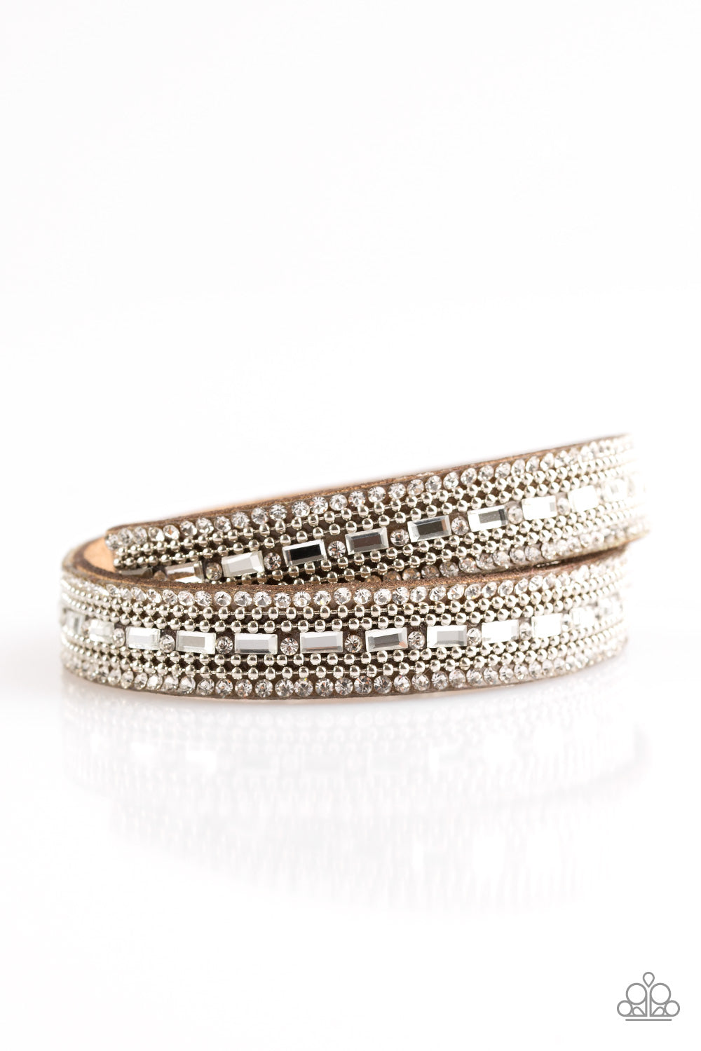 Featuring round and emerald style cuts, glassy white rhinestones are encrusted along a gray suede band. Rows of shimmery silver ball-chain are pressed into the glittery band for a sassy finish. The elongated band allows for a trendy double wrap design. Features an adjustable snap closure. Sold as one individual bracelet.
