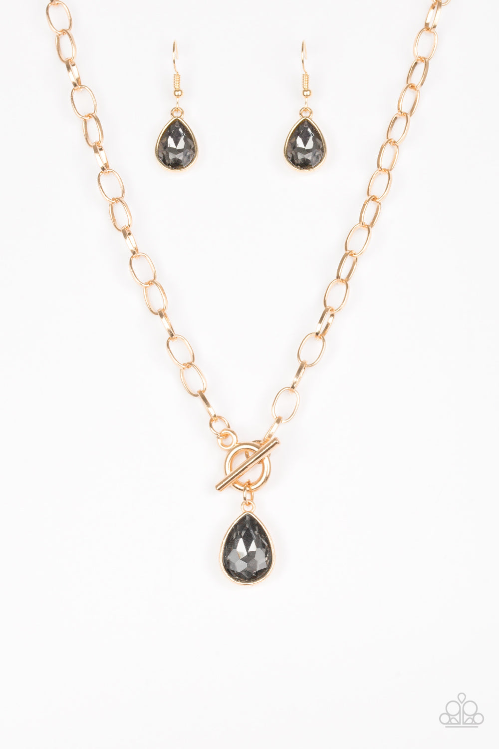 A smoky teardrop gem swings from the bottom of a shimmery gold chain, creating a classic pendant below the collar. Features a toggle closure. Sold as one individual necklace. Includes one pair of matching earrings.