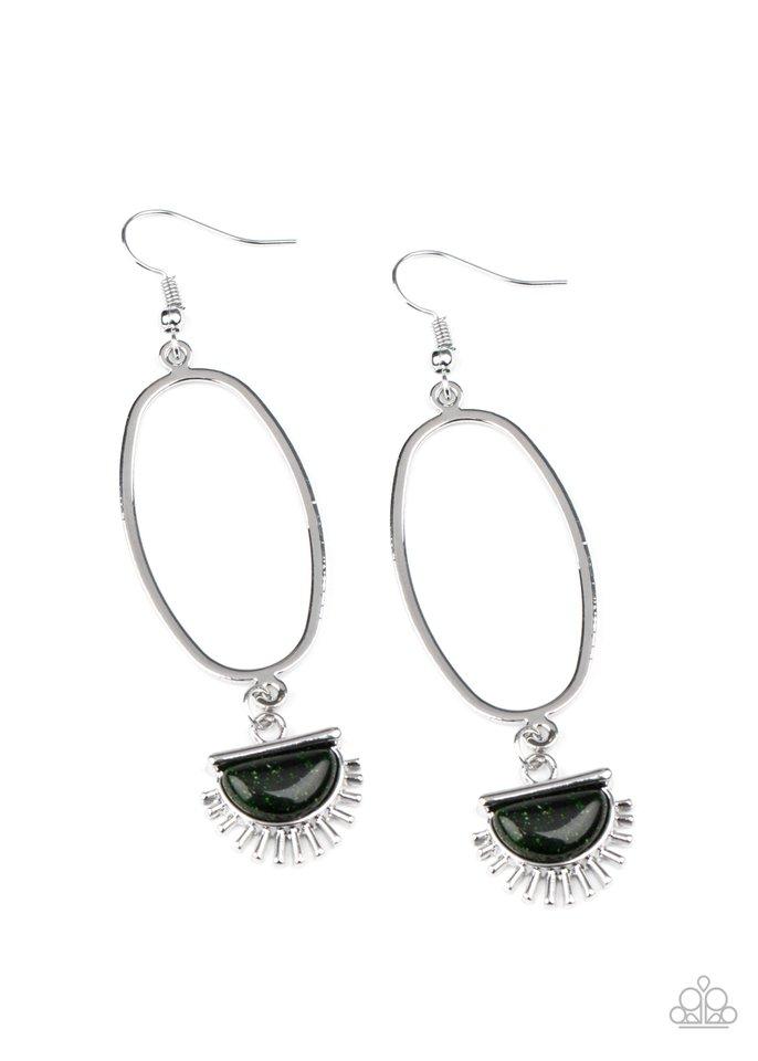 A silver sunburst charm with a glittery green stone center dangles from the bottom of an elongated oval hoop for a trendy vibe. Earring attaches to a standard fishhook fitting. Sold as one pair of earrings.
