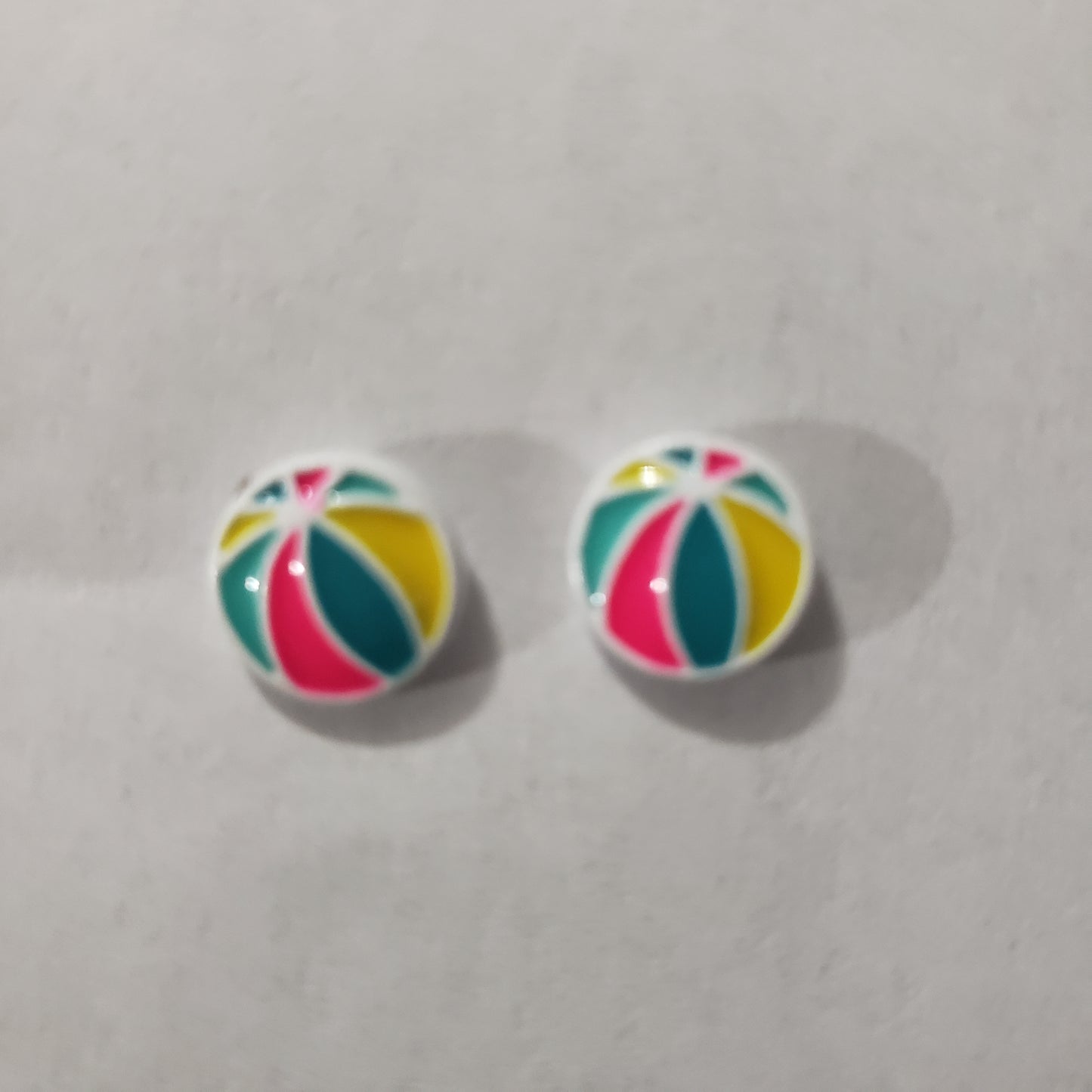 Beach themed post back earrings. The summery frames feature multi-colored beach balls. Earrings attach to standard post fittings. Sold as one set of earrings.