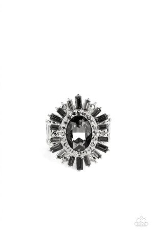 A large smoky rhinestone sparkles inside a ring of dainty hematite rhinestones. Emerald cut hematite and smoky gray rhinestones fan out from the dazzling center, exploding into a stellar centerpiece atop the finger. Features a stretchy band for a flexible fit. Sold as one individual ring.