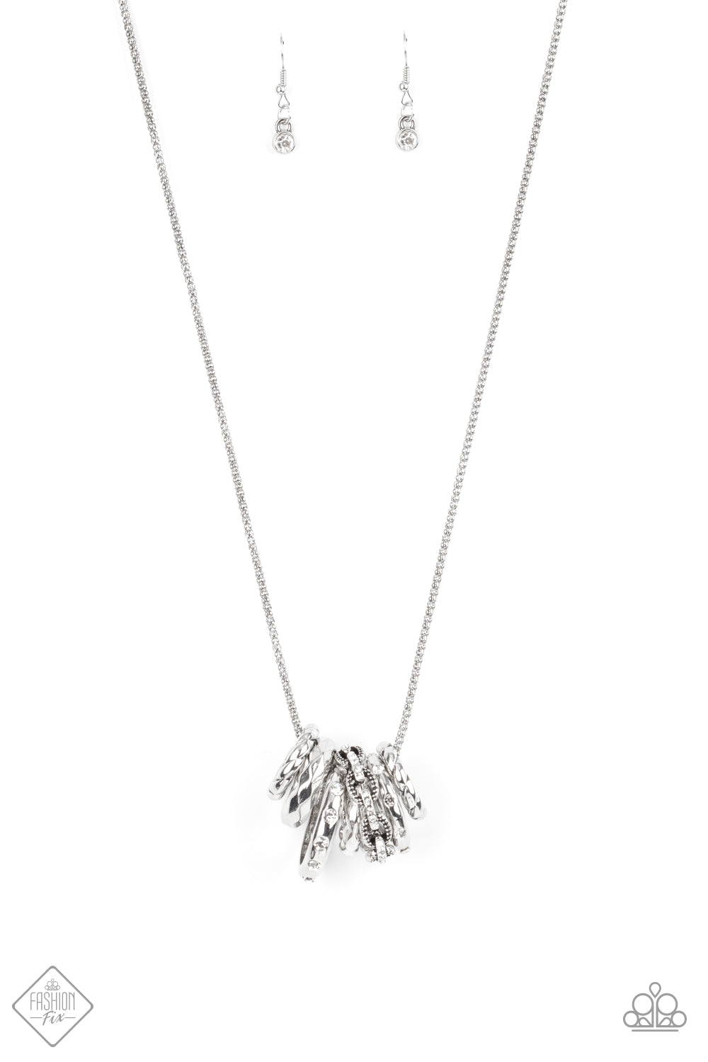 Featuring white rhinestones, faceted surfaces, twisted finishes, and chain-like patterns, an edgy collection of mismatched silver rings glide along a lengthened silver popcorn chain in a glamorously gritty finish. Features an adjustable clasp closure. Sold as one individual necklace. Includes one pair of matching earrings.