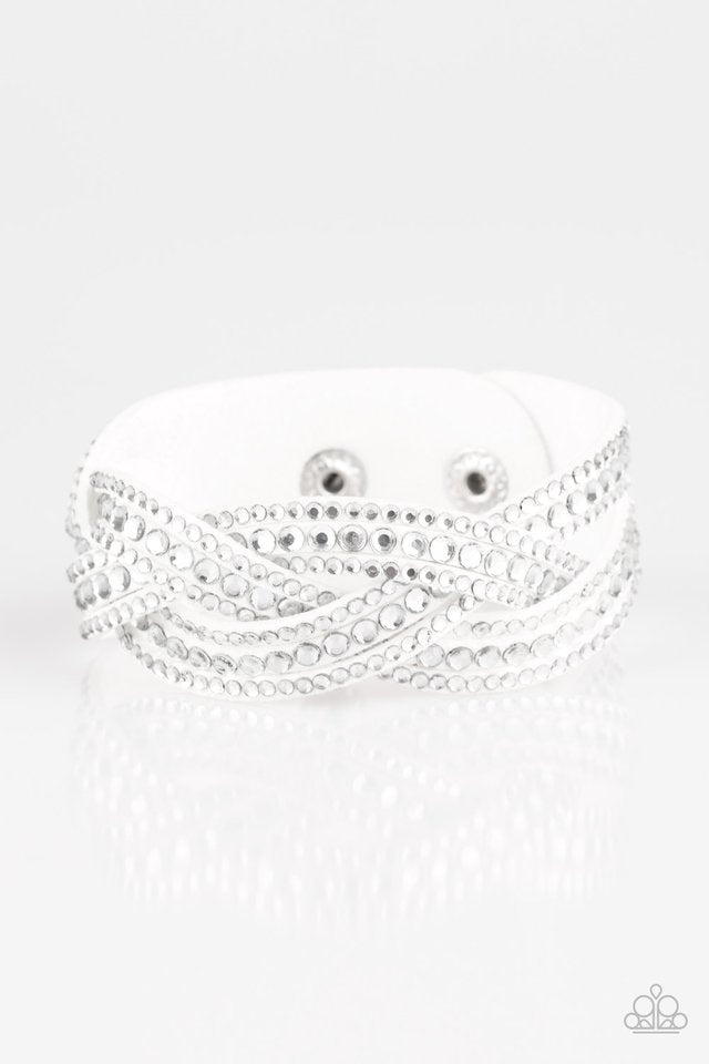 Varying in size, glassy white rhinestones are encrusted along interwoven white suede bands, creating blinding shimmer across the wrist. Features an adjustable snap closure. Sold as one individual bracelet.