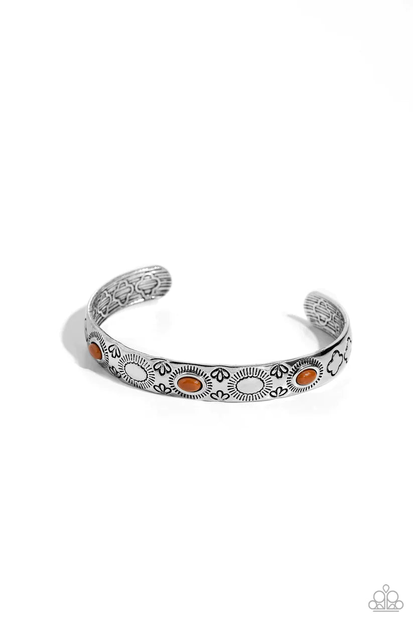 A trio of oval Adobe beads are pressed into the centers of shimmery sunbursts stamped across the front of a dainty silver cuff radiating with desert patterns, creating an earthy pop of color around the wrist. Sold as one individual bracelet.