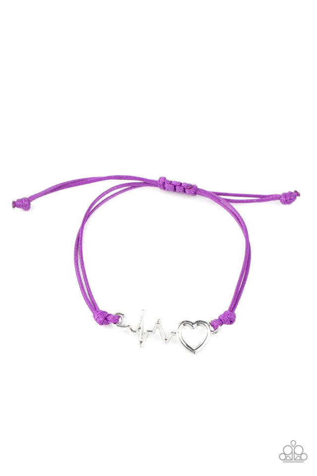 Shiny purple cording knots around a pulsing silver heart charm, creating a charming centerpiece atop the wrist. Features an adjustable sliding knot closure. Sold as one individual bracelet.