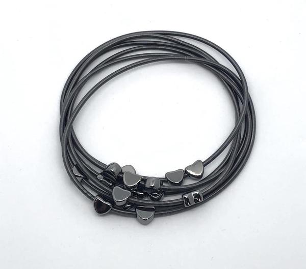 Dainty black hearts slide along interlocking stretchy spring-like wires, creating whimsical layers across the wrist.
Sold as one individual bracelet.