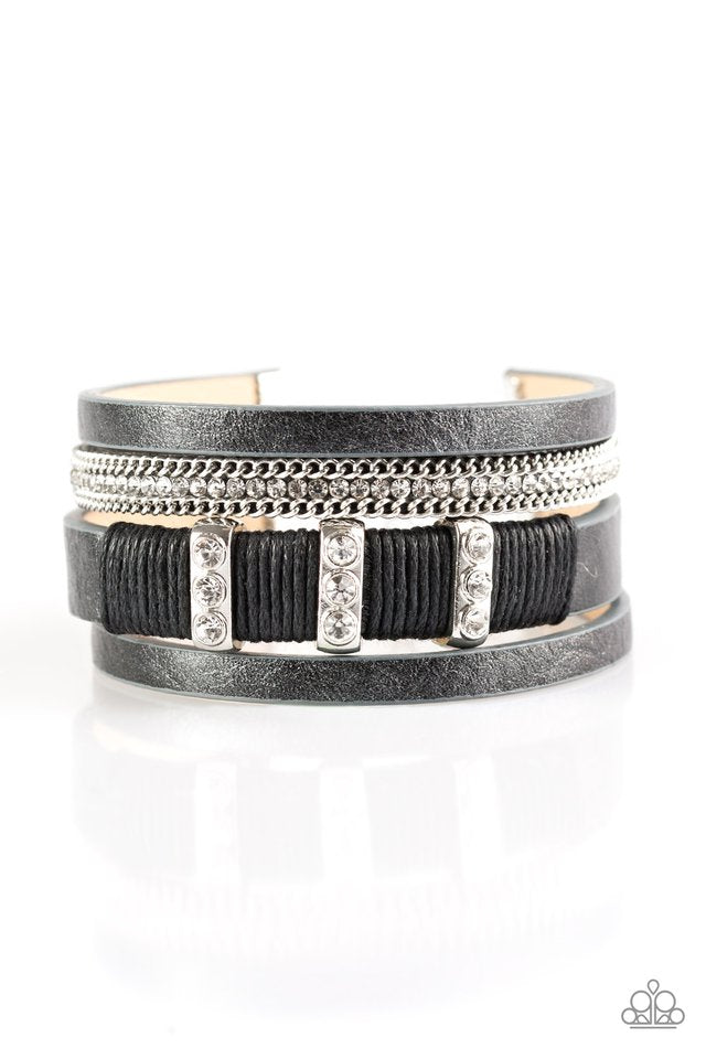 Paparazzi Accessories Bracelet: Metallic black leather strands layer across the wrist. Infused with silver chain and white rhinestone accents, black cording knots around a leather strand, securing glittery white rhinestone frames in place for a sassy finish. Features an adjustable clasp closure. Sold as one individual bracelet.