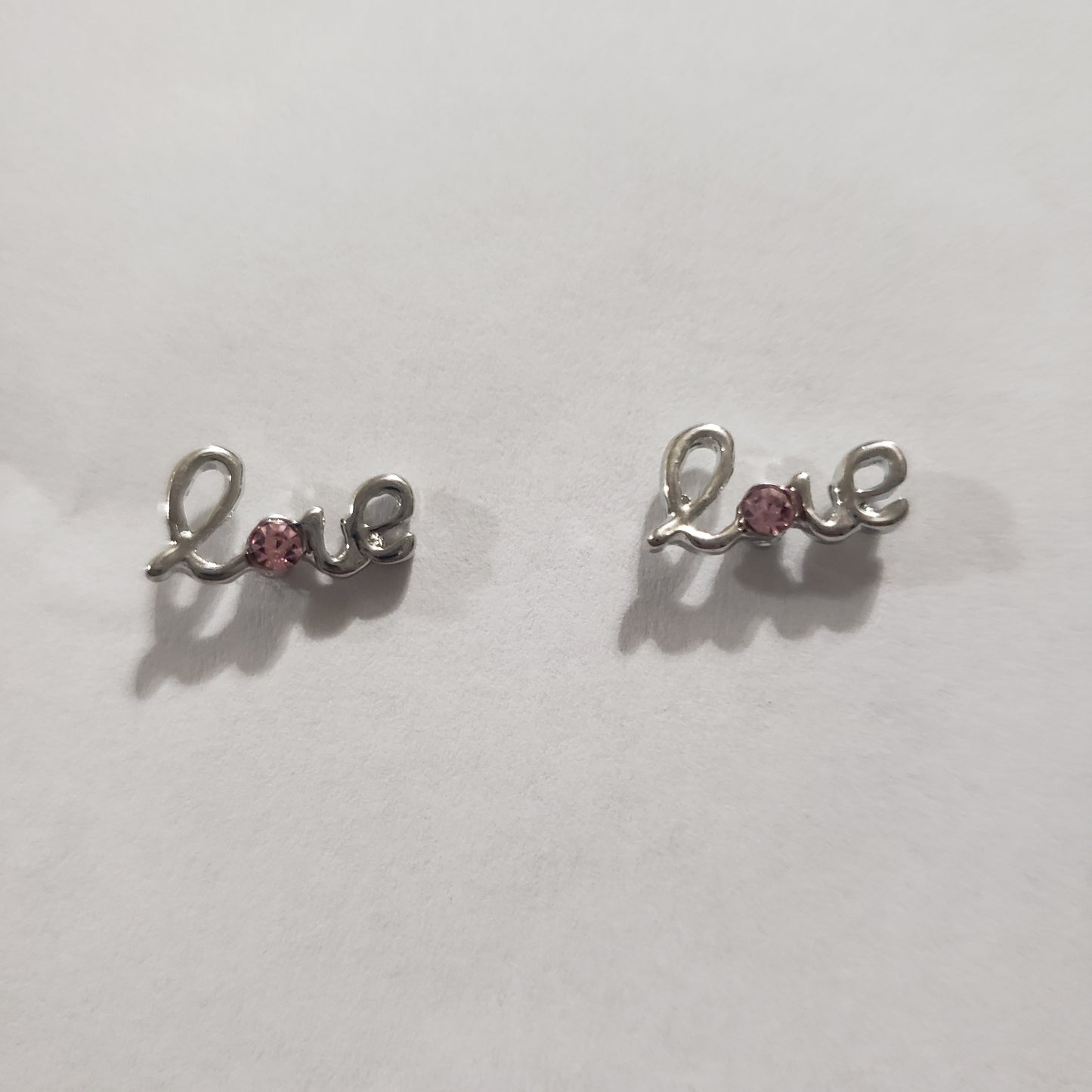 Kid's silver earrings with the word LOVE and a pink rhinestone in the letter "O"