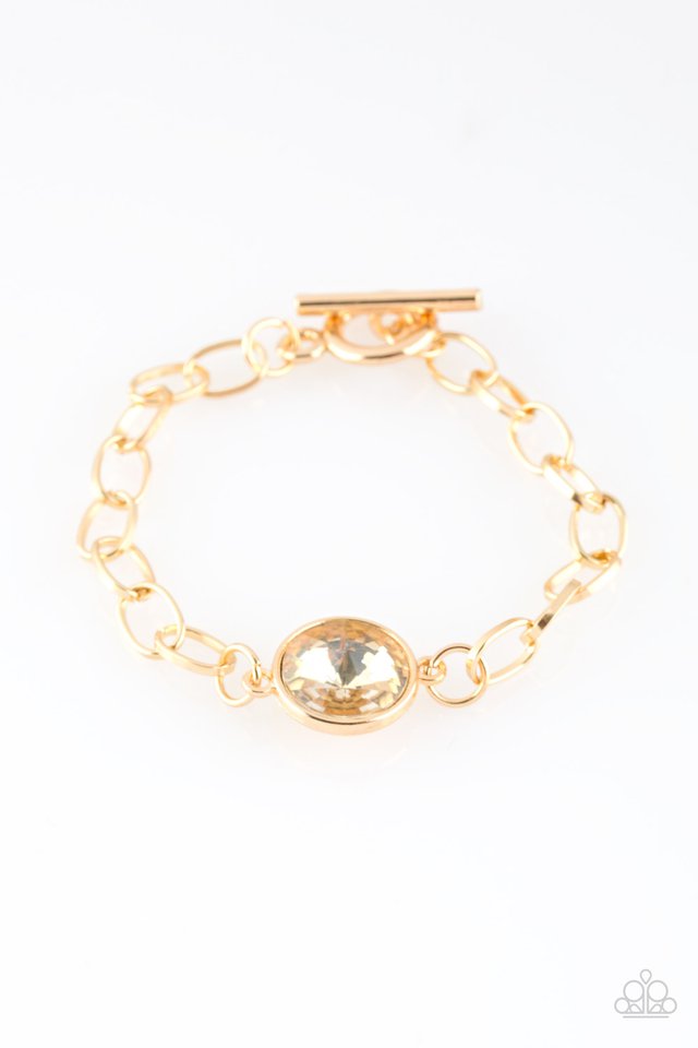 An oversized white gem attaches to a bold gold chain, creating a dramatic centerpiece atop the wrist. Features an adjustable clasp closure. Sold as one individual bracelet.