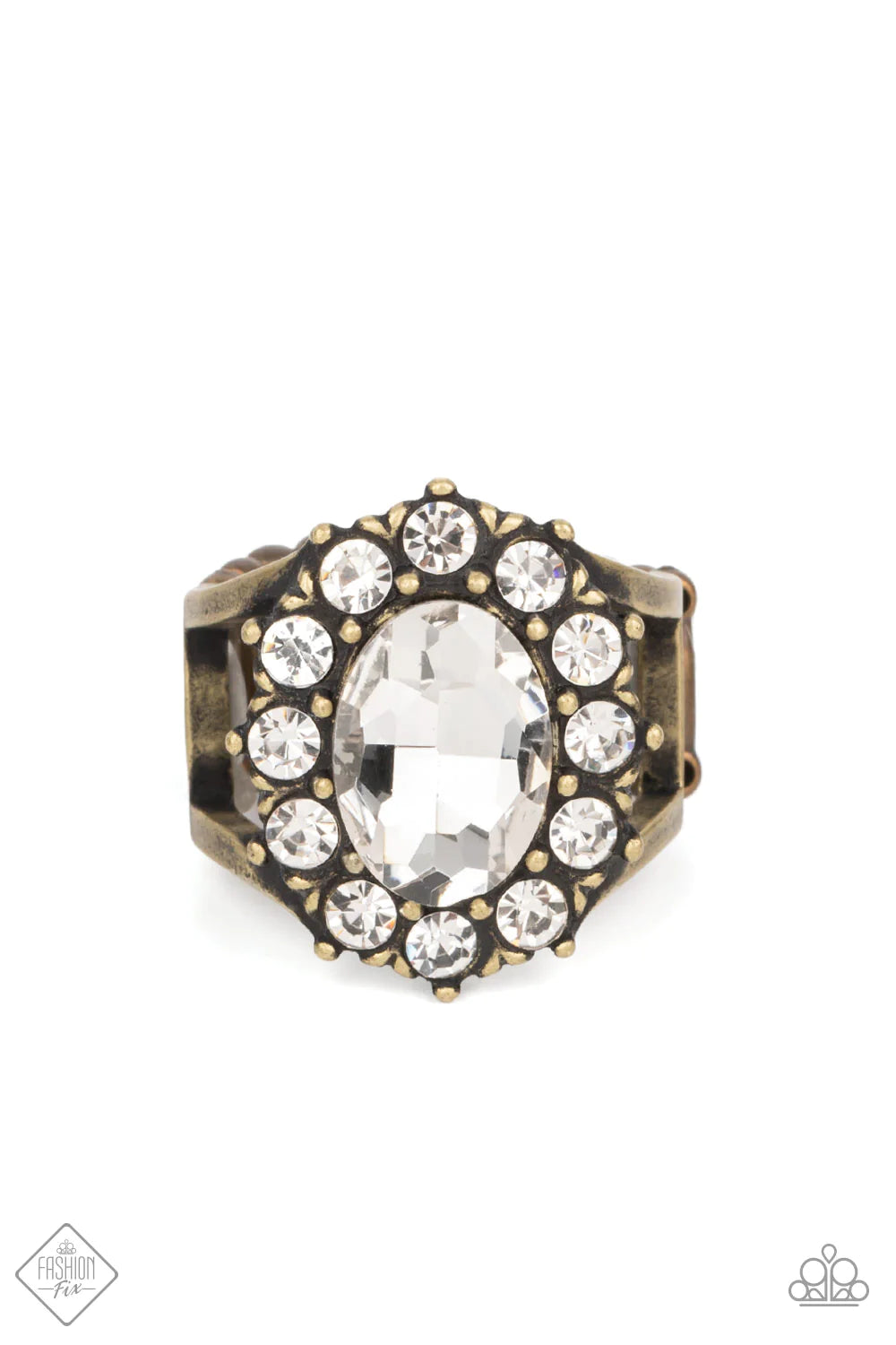 A dauntless oval rhinestone is encircled by dainty sparkling gems. Accented with petite antiqued brass studs, the dramatic design joins with an airy layered brass band to create a captivating arrangement atop the finger. Features a stretchy band for a flexible fit. Sold as one individual ring.