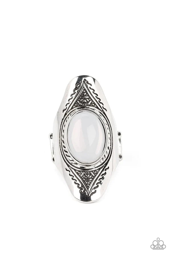 An oversized, glassy, opal bead is pressed into the center of a dramatically elongated silver frame. Triangular patterns are etched into the frame as it folds around the finger, resulting in an ethereal pop of color atop the finger. Features a stretchy band for a flexible fit. Sold as one individual ring.