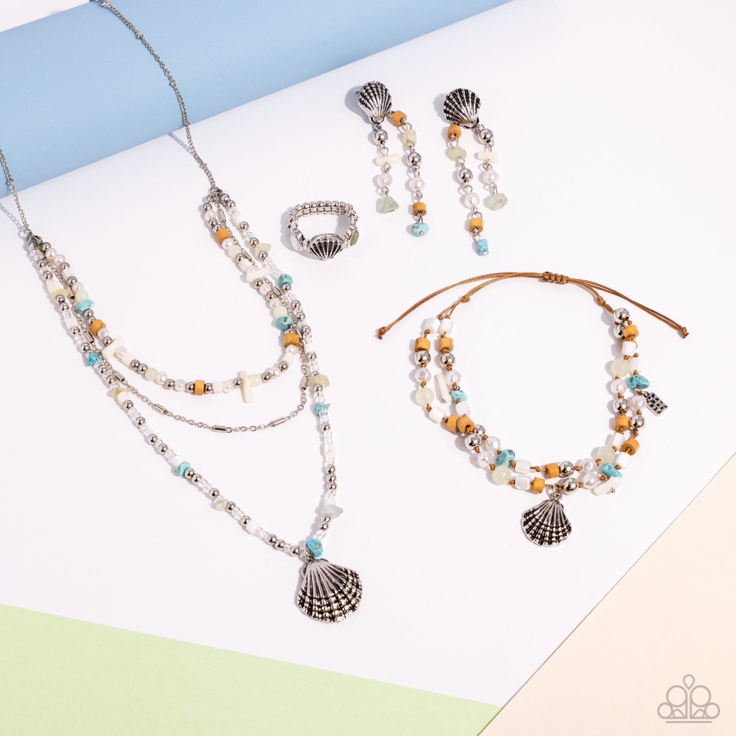 Women's silver necklace with silver shell pendant and blue crackleston, white, and silver beads, matching bracelet with brown leather pull strings, matching earrings, and a silver shell ring