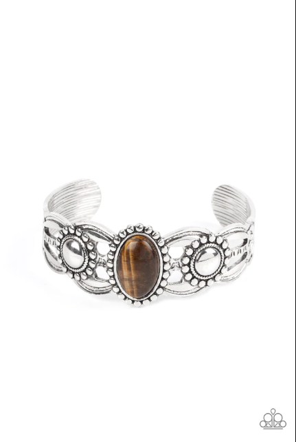 An oval Tiger's eye stone is pressed into the center of a studded silver frame atop an airy silver cuff embellished in studded sun-like frames for an earthy pop of seasonal color around the wrist. Sold as one individual bracelet.