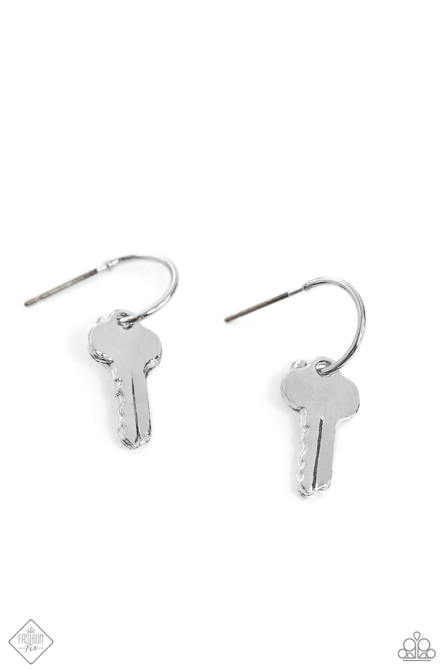 A small, skinny, silver hoop curves around the ear in a timeless fashion. A silver ball is affixed to the end of the hoop, reminiscent of a barbell fitting. A silver key charm slides along the curvature of the hoop, adding a subtle hint of industrial movement. Earring attaches to a standard post fitting. Hoop measures approximately 1/2" in diameter. Sold as one pair of hoop earrings.