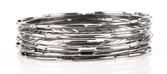 Featuring smooth, serrated, and pinched finishes, mismatched silver bangles stack across the wrist for a bold industrial look. Sold as one set of nine bracelets.