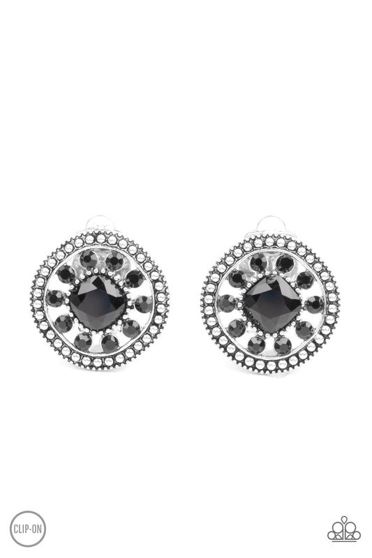 Featuring an oversized center, a black rhinestone encrusted flower blooms across the silver center of a studded frame for a sparkly finish. Earring attaches to a standard clip-on fitting.  Sold as one pair of clip-on earrings.