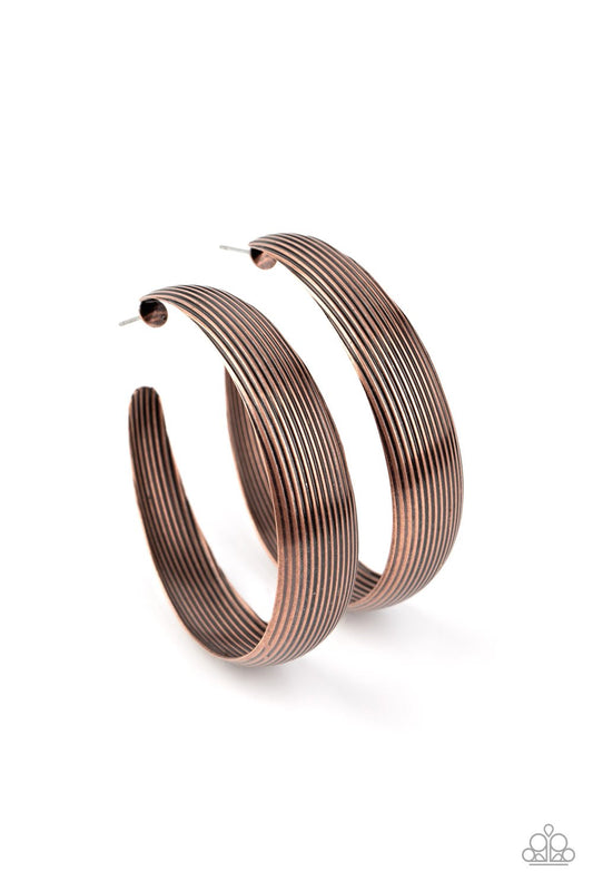 Lined in antiqued ridges, a thick copper hoop curls around the ear for an authentically rustic look. Earring attaches to a standard post fitting. Hoop measures approximately 2 ¼” in diameter.  Sold as one pair of hoop earrings.
