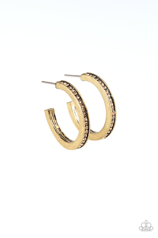 A dainty brass hoop is encrusted in golden topaz rhinestones for a classic look. Earring attaches to a standard post fitting. Hoop measures 1" in diameter.  Sold as one pair of hoop earrings.
