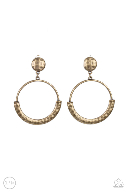 The bottom of an antiqued brass hoop is covered with a bowing hammered frame at the bottom of a hammered brass disc, creating a rustic lure. Earring attaches to a standard clip-on fitting.  Sold as one pair of clip-on earrings.