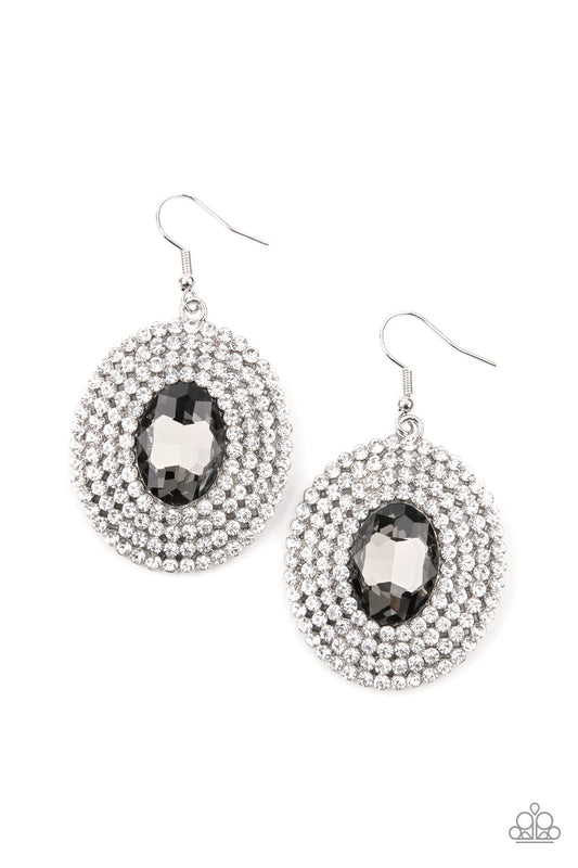A smoky oval gem is pressed into the center of ring after ring of glassy white rhinestones, radiating out into a glamorously glittering centerpiece. Earring attaches to a standard fishhook fitting.  Sold as one pair of earrings.