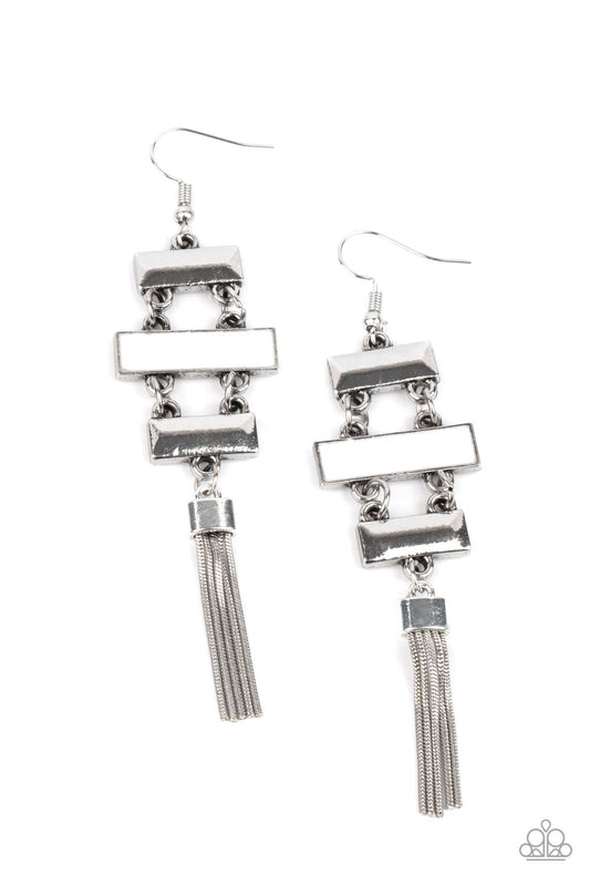 Glistening silver rectangular frames link with a white rectangular frame, connecting into a sleekly stacked lure. A shimmery silver tassel dances from the bottom, adding a hint of whimsicality to the colorful display. Earring attaches to a standard fishhook fitting.  Sold as one pair of earrings.