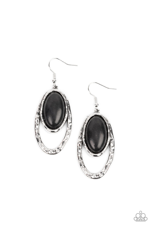 An oval black stone is pressed into a hammered silver fitting that attaches to the top of a hammered silver oval frame, creating a rustic lure. Earring attaches to a standard fishhook fitting.  Sold as one pair of earrings.