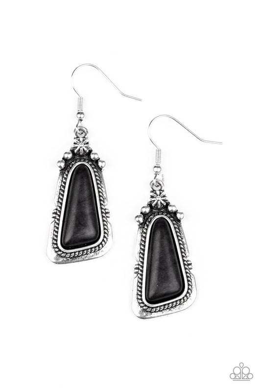 An imperfect black stone is pressed into the center of a studded silver frame featuring silver rope-like texture. Earring attaches to a standard fishhook fitting.  Sold as one pair of earrings.