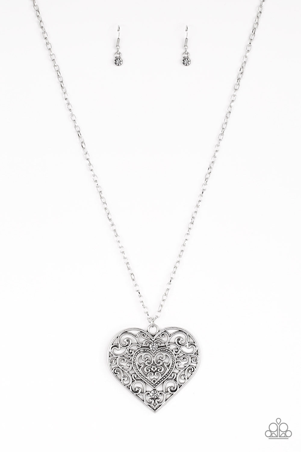 Dotted with smoky rhinestones, an oversized heart frame radiating with glistening filigree detail swings from the bottom of a lengthened silver chain for a vintage inspired look. Features an adjustable clasp closure.  Sold as one individual necklace. Includes one pair of matching earrings.