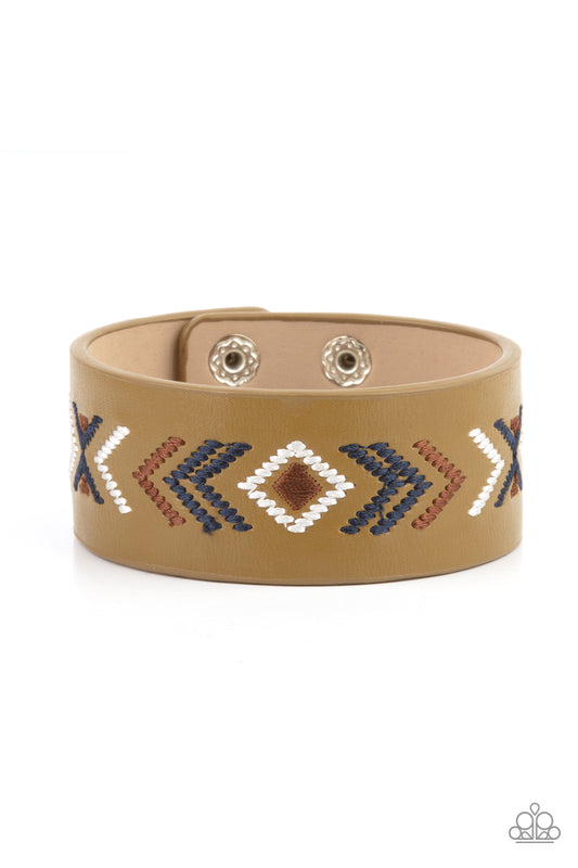 Blue, brown, and white thread is stitched across the front of a Willow leather band, creating a colorful tribal inspired pattern. Features an adjustable snap closure.  Sold as one individual bracelet.