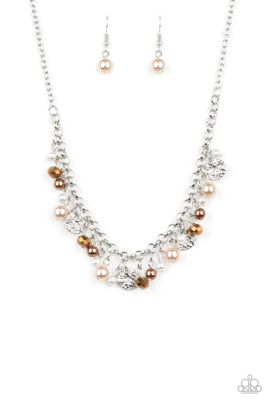 Pearly white and brown beads, aurum crystal-like gems, and hammered silver discs swing from a bold silver chain, creating a refined fringe below the collar. Features an adjustable clasp closure.  Sold as one individual necklace. Includes one pair of matching earrings.