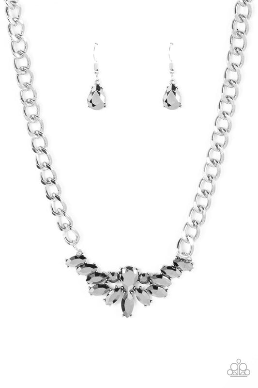 Glitzy marquise cut hematite rhinestones fan out from the bottom of an oversized teardrop hematite rhinestone, resulting in a gritty pendant at the bottom of a chunky silver chain for a sassy statement. Features an adjustable clasp closure.  Sold as one individual necklace. Includes one pair of matching earrings.