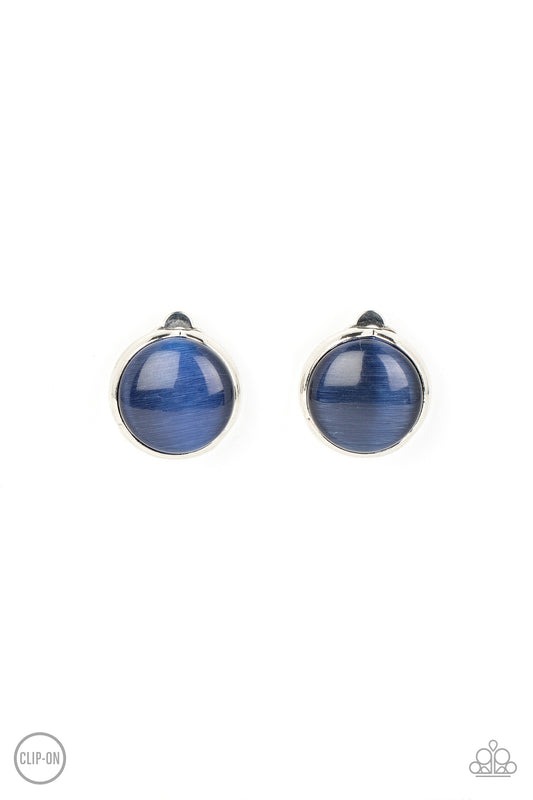 A blue cat's eye stone coolly shimmers inside an imperfect silver frame, resulting in an ethereal centerpiece. Earring attaches to a standard clip-on fitting.  Sold as one pair of clip-on earrings.