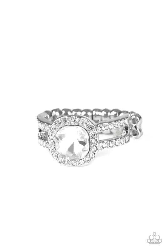 Bordered in a ring of glassy white rhinestones, a radiant white rhinestone nestles atop two white rhinestone encrusted silver bands for a timeless shimmer. Features a dainty stretchy band for a flexible fit.  Sold as one individual ring.
