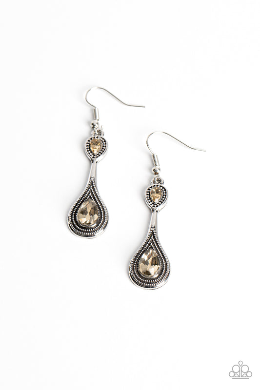 Two golden topaz rhinestones adorn the top and bottom of an extended silver lure radiating with studded textures, resulting in an ethereal dazzle. Earring attaches to a standard fishhook fitting.  Sold as one pair of earrings.
