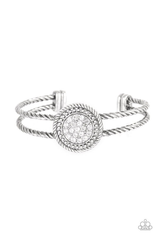Brushed in an antiqued shimmer, twisted silver bars arc across the finger, coalescing into an airy cuff. Radiating in silver studs and glittery white rhinestones, a round silver frame adorns the center for an edgy look.  Sold as one individual bracelet.