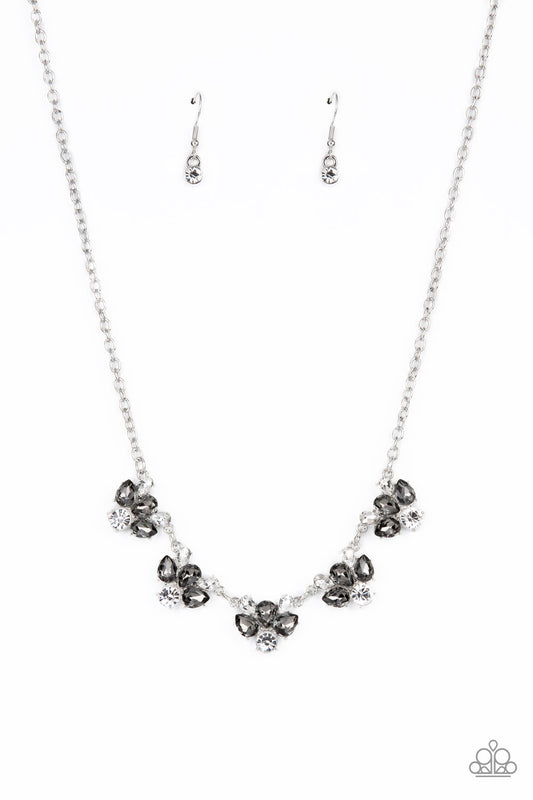 Featuring round and teardrop cuts, white and smoky rhinestones delicately link into a sparkling statement piece that results into an envious glow below the collar. Features an adjustable clasp closure.  Sold as one individual necklace. Includes one pair of matching earrings.