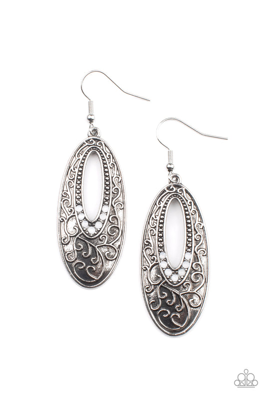 Dainty silver studs fade into dewy white rhinestones around the airy center of an oval silver frame that is embossed in vine-like scroll, creating an ethereally whimsical frame. Earring attaches to a standard fishhook fitting.  Sold as one pair of earrings.