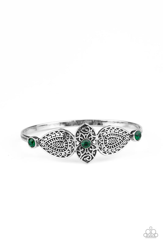 Embossed in decorative filigree, leafy silver frames connect into a whimsical centerpiece atop a silver bangle. Glittery green rhinestones dot the ornate centerpiece, adding colorful sparkle to the dainty piece.  Sold as one individual bracelet.