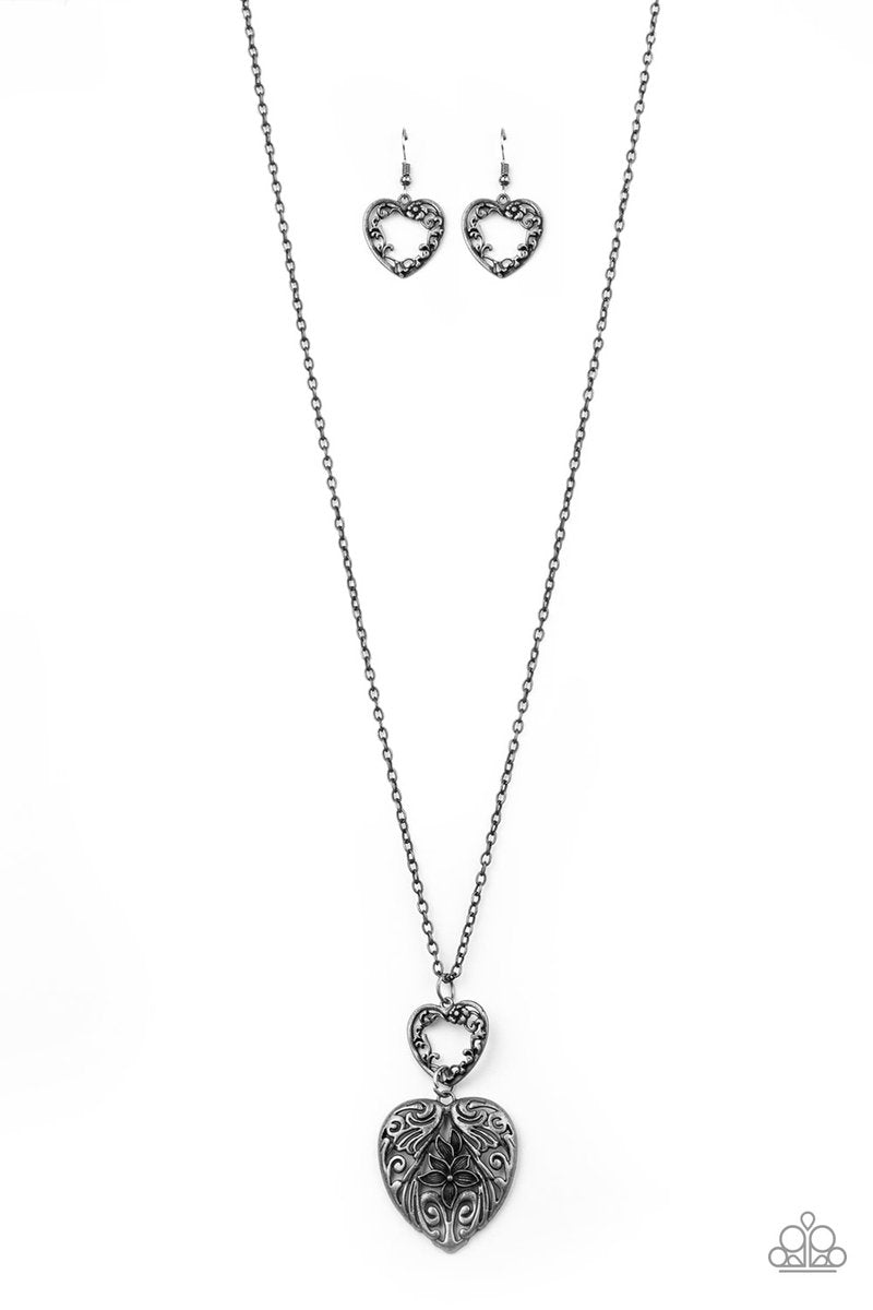 Swirling with ornate floral filigree details, a pair of tin finished silver heart frames link at the bottom of a lengthened silver chain for a vintage inspired look. Features an adjustable clasp closure.  Sold as one individual necklace. Includes one pair of matching earrings.