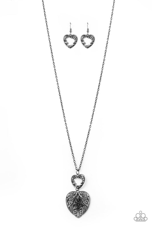 Swirling with ornate floral filigree details, a pair of tin finished silver heart frames link at the bottom of a lengthened silver chain for a vintage inspired look. Features an adjustable clasp closure.  Sold as one individual necklace. Includes one pair of matching earrings.