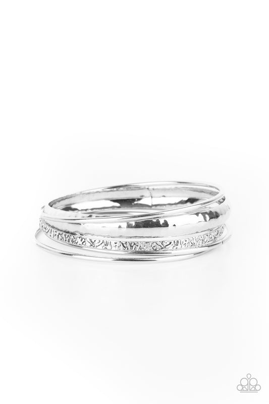 A mismatched collection of plain, hammered, and textured silver bangles stack across the wrist for an edgy industrial look.  Sold as one set of five bracelets.