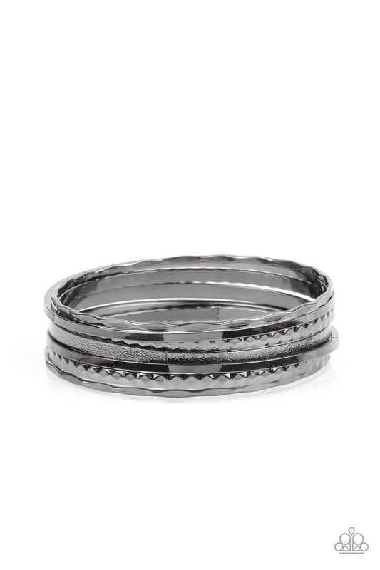 Varying in hammered, diamond-cut, and shiny finishes, a collection of mismatched gunmetal bangles stack across the wrist for an intense industrial look.  Sold as one set of seven bracelets.