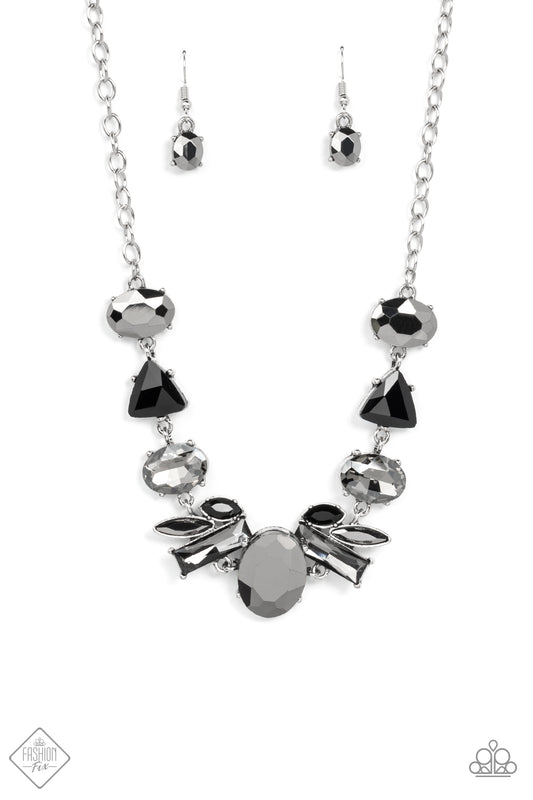 Anchored by a glassy oval hematite gem, a mismatched collection of lustrous hematite, smoky, and black rhinestones in various modern shapes and sizes link together across the collar. The gritty display gives way to a classic silver chain for a sleek finish. Features an adjustable clasp closure.  Sold as one individual necklace. Includes one pair of matching earrings.