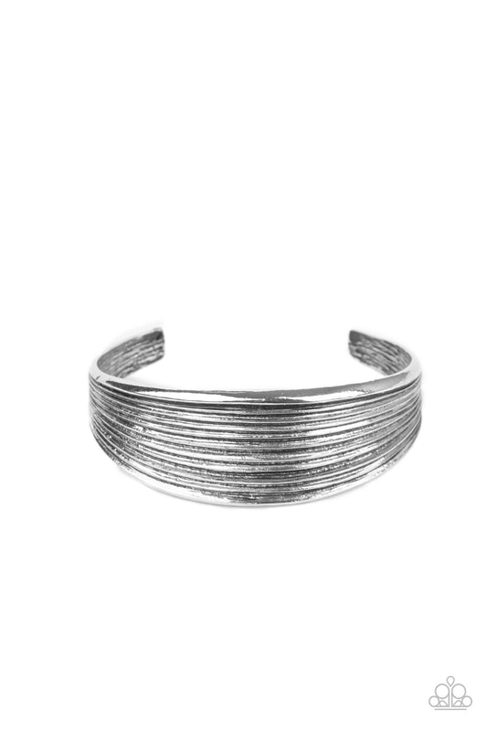 Featuring beveled linear texture, a thick silver cuff delicately curls around the wrist for a dash of rustic refinement.  Sold as one individual bracelet.
