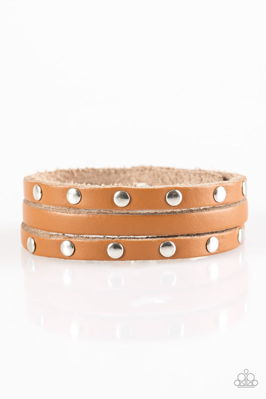 A shiny brown leather band is spliced into three strands. Flat silver beads are studded down the outer strands, adding a rugged finish to the urban palette. Features an adjustable snap closure.  Sold as one individual bracelet.