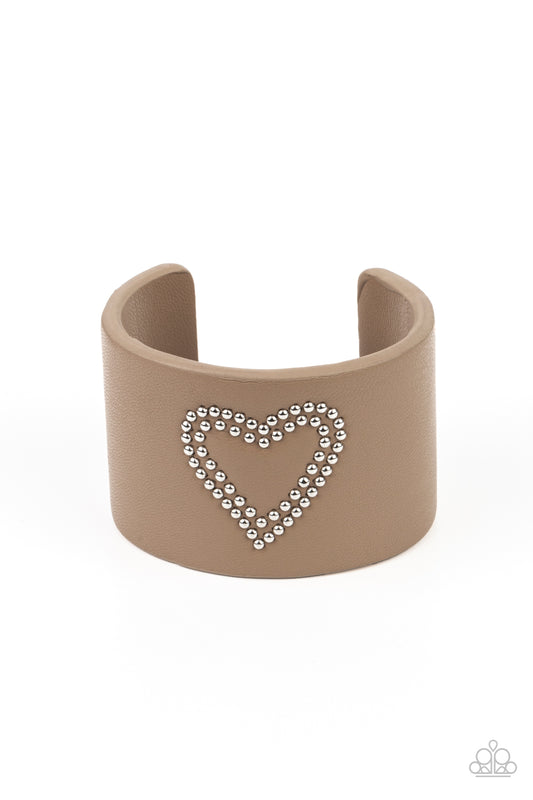 The center of a brown leather cuff is studded in a charming heart pattern, creating a rustically romantic look around the wrist.  Sold as one individual bracelet.