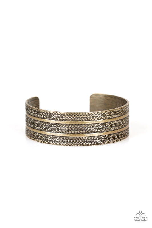 Brushed in an antiqued shimmer, flat brass ribbons race across a brass cuff embossed in tactile textures for a tribal inspired flair. Sold as one individual bracelet.